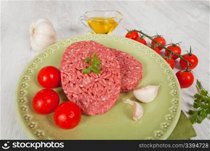 Fresh raw hamburger meat with parsley served on a green plate