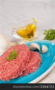 Fresh raw hamburger meat with parsley served on a plate