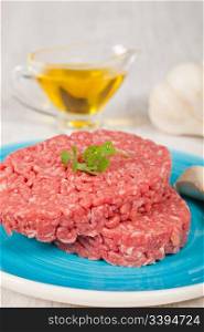Fresh raw hamburger meat with parsley served on a plate