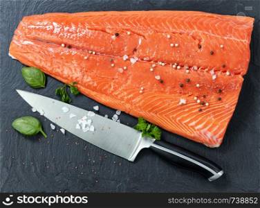 Fresh raw king salmon on natural stone with herbs and seasoning