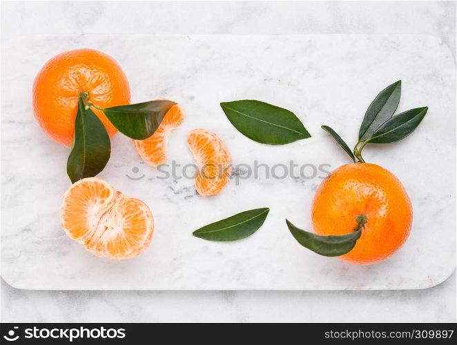 Fresh raw mandarin tangerines fruit with leaves on marble background