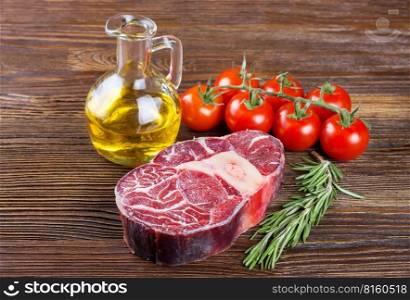 Fresh raw meat beef steak with bone with rosemary, tomatoes and olive oil on brown wooden background. cooking ingredients.. Cooking ingredients. Fresh raw meat beef steak with bone.