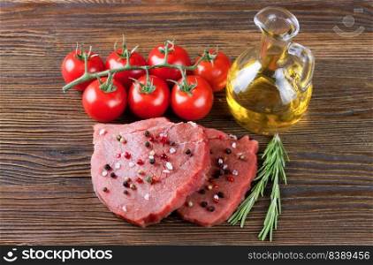 Fresh raw meat beef steak with bone with spices, rosemary, tomatoes and olive oil on brown wooden background. cooking ingredients. Top view, flat lay. Cooking ingredients. Fresh raw meat beef steak with bone.
