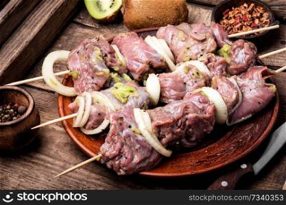 Fresh raw meat skewers kebabs on plate.Meat prepared for marinating on cutting board. Skewers of shish kebab