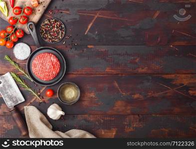 Fresh raw minced homemade farmers grill beef burger in frying pan with spices and herbs and meat hatchet on wooden board. Space for text