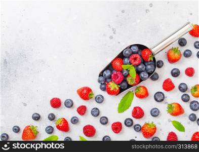 Fresh raw organic berries in steel scoop spoon on kitchen table. Space for text. Top view. Strawberry, Raspberry, Blueberry and Mint leaf