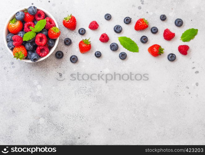 Fresh raw organic berries in white ceramic bowl on kitchen table background. Space for text. Strawberry, Raspberry, Blueberry and Mint leaf