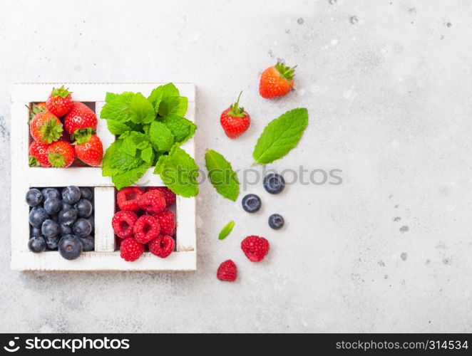 Fresh raw organic berries in white wintage wooden box on kitchen table background. Space for text. Strawberry, Raspberry, Blueberry and Mint leaf