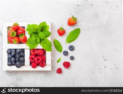 Fresh raw organic berries in white wintage wooden box on kitchen table background. Space for text. Strawberry, Raspberry, Blueberry and Mint leaf