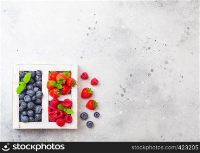 Fresh raw organic berries in white wintage wooden box on kitchen table background. Space for text. Strawberry, Raspberry, Blueberry and Mint leaf