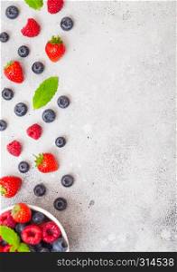 Fresh raw organic berries isolated in white ceramic bowl on kitchen table background. Space for text. Strawberry, Raspberry, Blueberry and Mint leaf