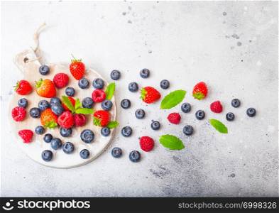 Fresh raw organic berries on round vintage board background. Strawberry, Raspberry, Blueberry and Mint leaf