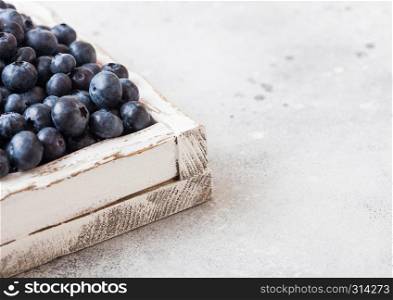 Fresh raw organic blueberries in vintage wooden box on kitchen background.