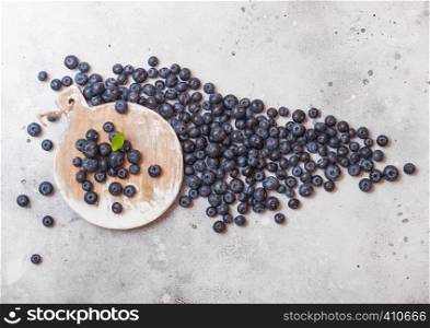 Fresh raw organic blueberries on round vintage wooden board on stone kitchen background. Space for text