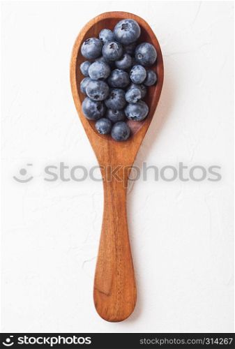Fresh raw organic blueberries on wooden spoon on white kitchen background. Food concept.