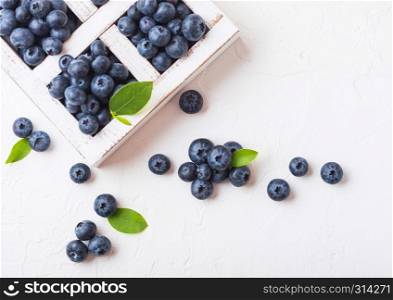 Fresh raw organic blueberries with leaf in vintage wooden box on kitchen background.