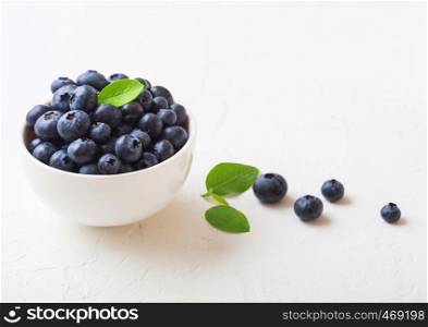 Fresh raw organic blueberries with leaf in white china bowl on white background. Macro