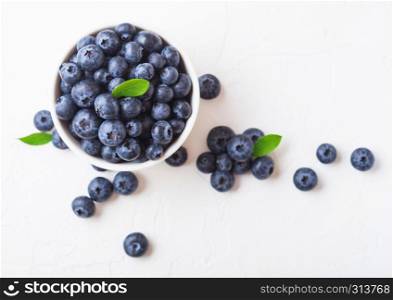 Fresh raw organic blueberries with leaf in white china bowl on white background. Top view