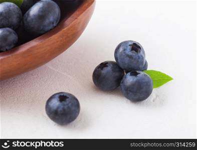 Fresh raw organic blueberries with leaf in wooden bowl on white background.