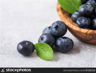 Fresh raw organic blueberries with leaf in wooden bowl on white background.