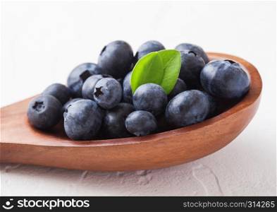 Fresh raw organic blueberries with leaf on wooden spoon on white kitchen background. Food concept.
