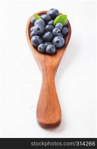Fresh raw organic blueberries with leaf on wooden spoon on white kitchen background. Food concept.