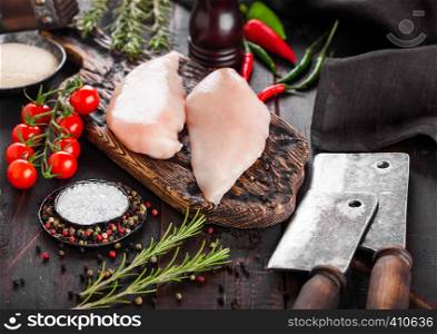 Fresh Raw Organic Chicken Fillet Breast on vintage board with meat hatchets and hammer with spices and herbs on wooden background.