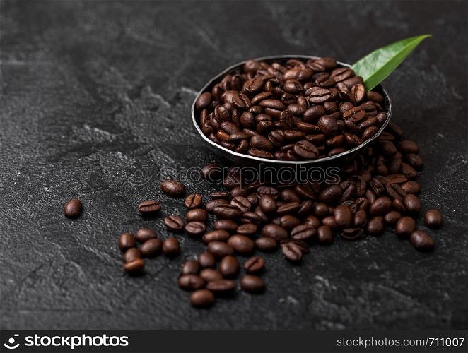 Fresh raw organic coffee beans with coffee trea leaf on black.
