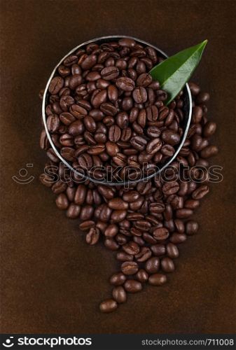 Fresh raw organic coffee beans with coffee trea leaf on brown.