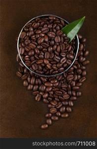 Fresh raw organic coffee beans with coffee trea leaf on brown.