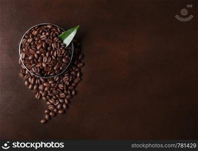 Fresh raw organic coffee beans with coffee trea leaf on brown. Space for text