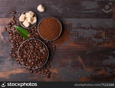 Fresh raw organic coffee beans with ground powder and cane sugar cubes on wood. Space for text