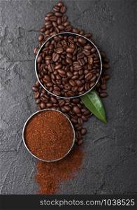 Fresh raw organic coffee beans with ground powder and coffee trea leaf on black