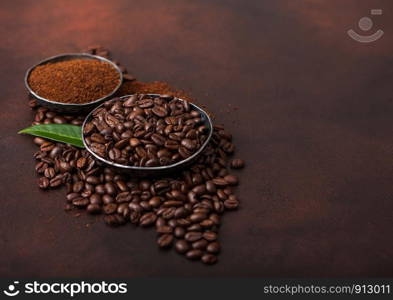 Fresh raw organic coffee beans with ground powder and coffee trea leaf on brown.
