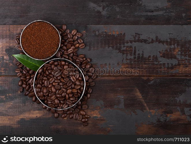 Fresh raw organic coffee beans with ground powder and coffee tree leaf on wood.