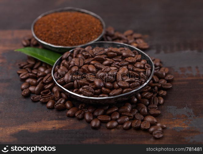 Fresh raw organic coffee beans with ground powder and coffee tree leaf on wood.