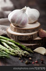 Fresh raw organic garlic with rosemary and asparagus on wooden background.
