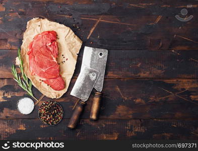 Fresh raw organic slice of braising steak fillet on chopping board with meat hatchets on wooden background. Space for text