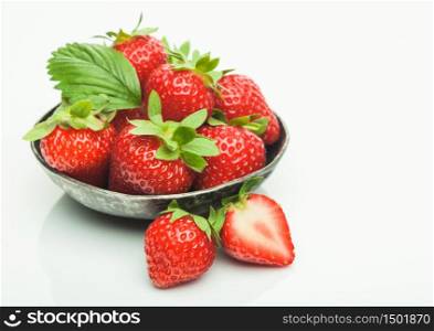 Fresh raw organic strawberries in steel bowl plate on white background with berries next to it. Macro
