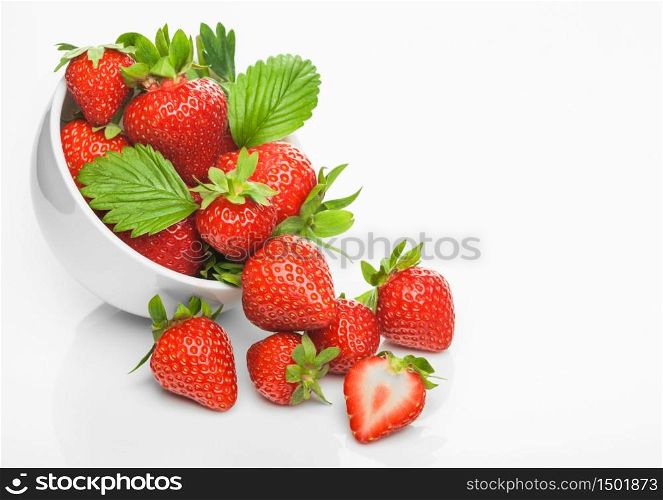 Fresh raw organic strawberries in white ceramic bowl plate on white background with berries next to it. Top view