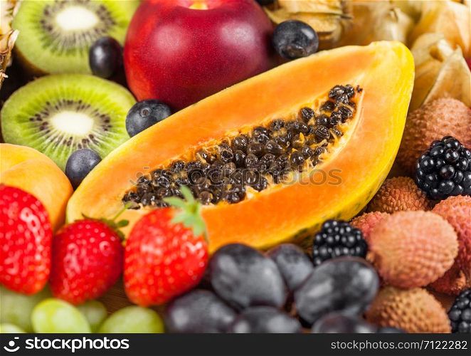 Fresh raw organic summer berries and exotic fruits. Macro. Close up. Pineapple, papaya, grapes, nectarine, orange, apricot, kiwi, lychees, cherry and physalis, raspberry. Top view