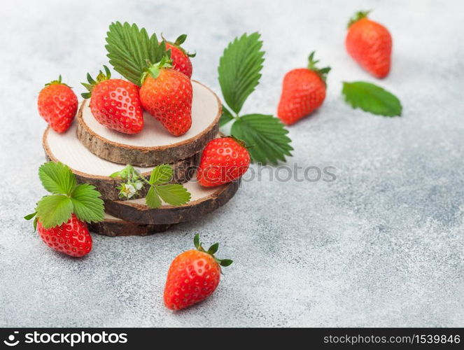 Fresh raw organic summer strawberries with a lot of vitamins and leaf on round timber boards on light background. Space for text