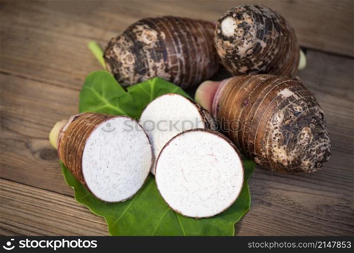 Fresh raw organic taro root ready to cook, Taro root with half slice on taro leaf and wooden background