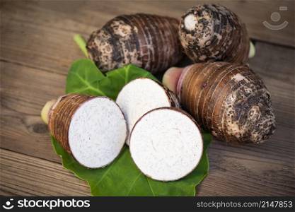 Fresh raw organic taro root ready to cook, Taro root with half slice on taro leaf and wooden background