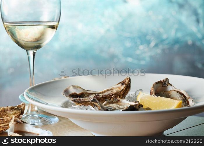 Fresh raw oysters on ice with lemon on a table with a glass of white wine. Fresh raw oysters on ice with lemon