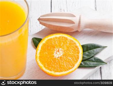 Fresh raw peeled oranges with hand wooden juice squeezer with leaves on white wooden background