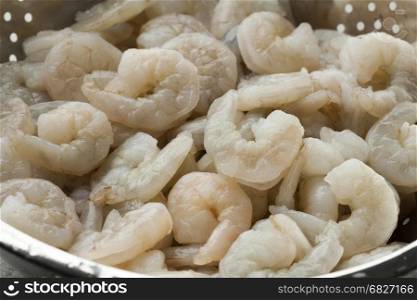 Fresh raw peeled shrimp in a colander close up