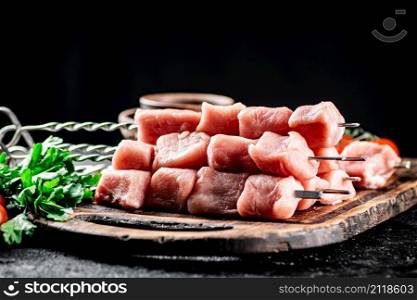 Fresh raw pork kebab on a cutting board. On a black background. High quality photo. Fresh raw pork kebab on a cutting board.