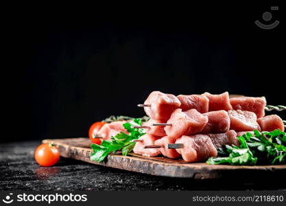 Fresh raw pork kebab on a cutting board. On a black background. High quality photo. Fresh raw pork kebab on a cutting board.