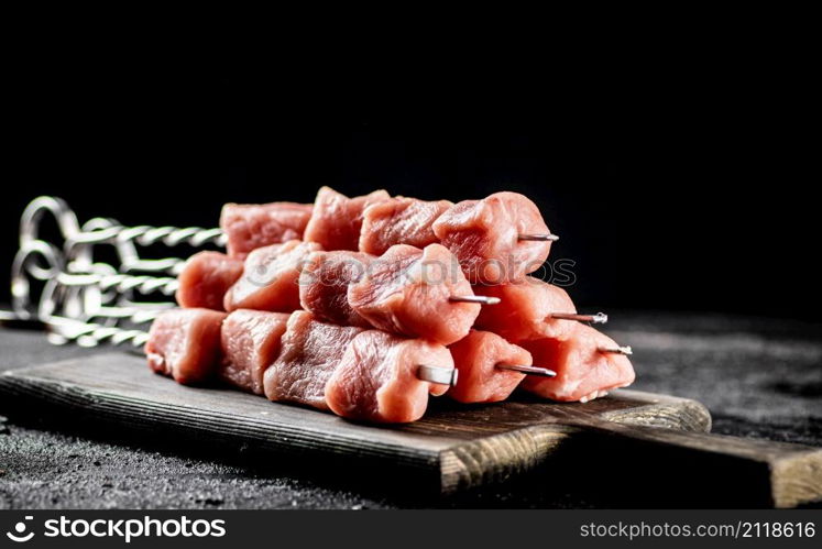 Fresh raw pork kebab on a cutting board. On a black background. High quality photo. Fresh raw pork kebab on a cutting board.